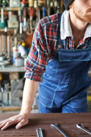 Portrait,Of,Unrecognizable,Bearded,Male,Leaning,On,Table,With,Wrenches